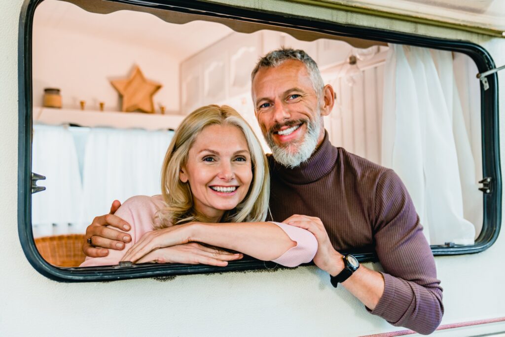 Happy elderly caucasian couple in the motorhome window smiling and hugging